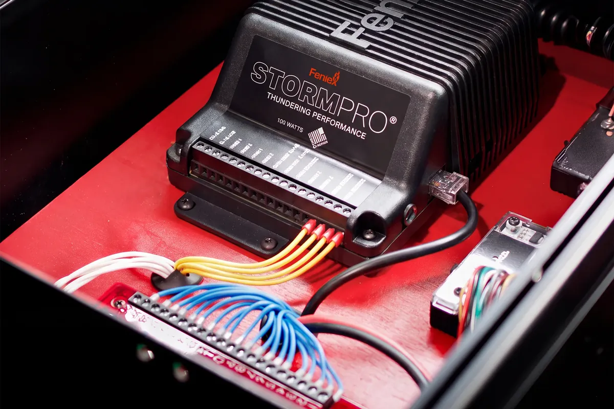 Feniex Storm Pro 100-watt siren amplifier mounted in an equipment box, with its wiring connected