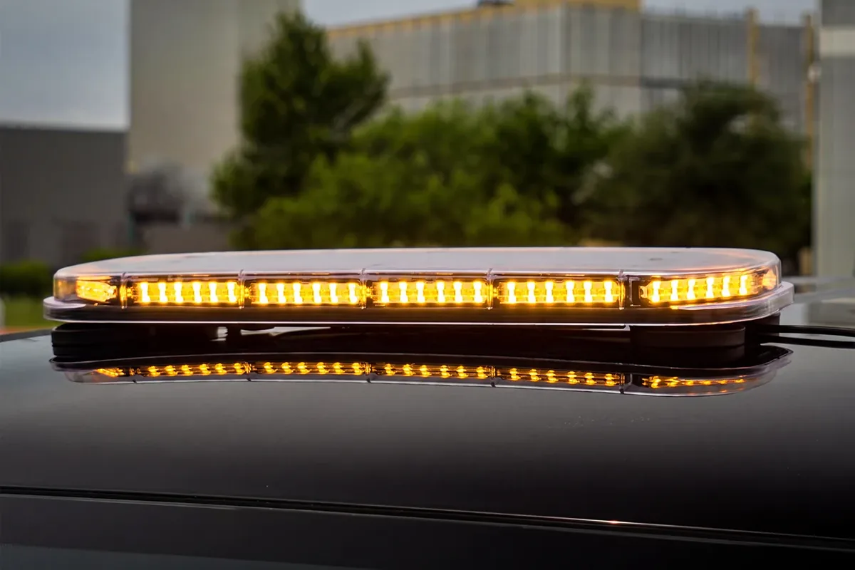 Feniex Quantum Mini 27 light bar flashing amber on the roof of a dark truck
