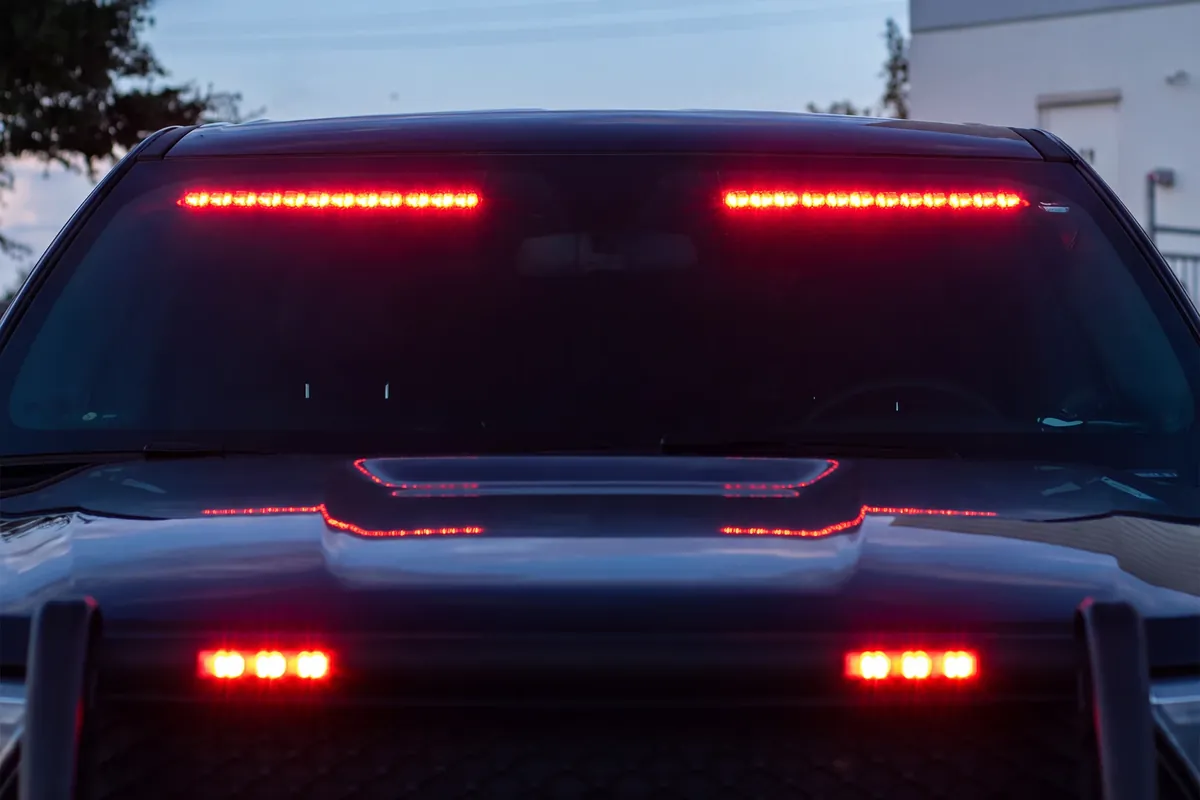 Dark pickup at dusk with a red Fusion Interior lightbar across the top of the windshield and red lights in the grille