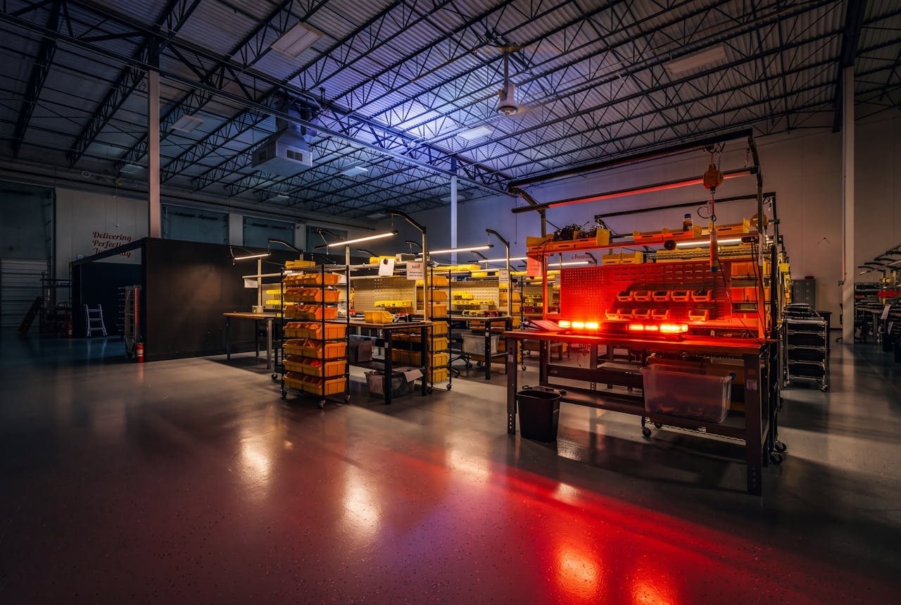 The Feniex assembly floor at night, task lights over each bench and a lightbar under test firing red.