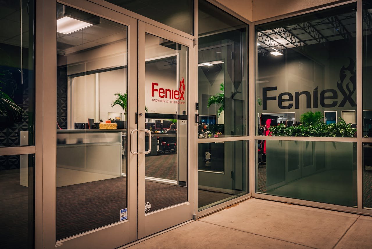 The Feniex entrance doors at night, warm interior light spilling out onto the concrete.