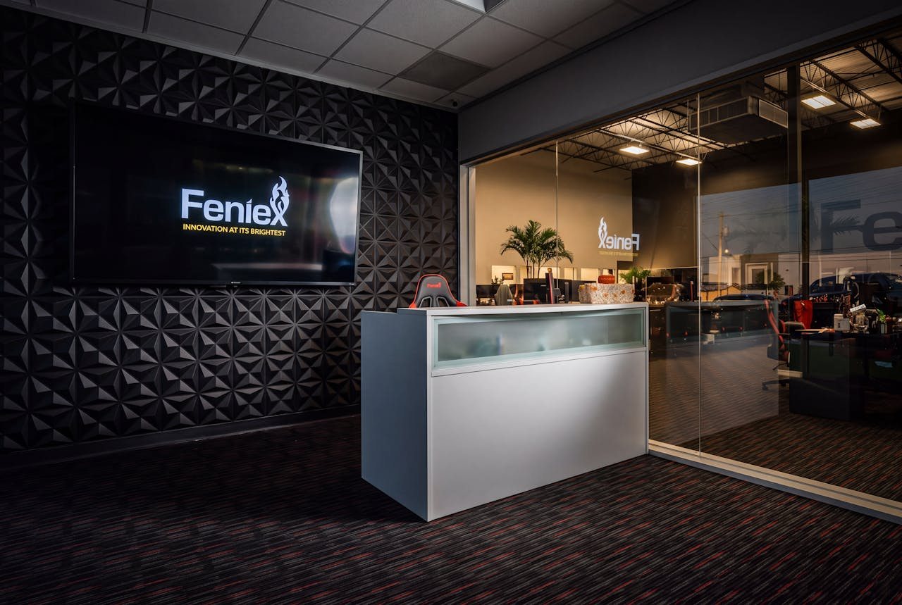 The Feniex reception at night, the wall screen lit and raking across a faceted black feature wall.